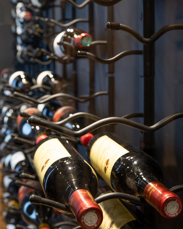 Classic wine wall in glass-enclosed cellar made with modular metal wine racks, stylish home wine storage for kitchen, living room or home bar.
