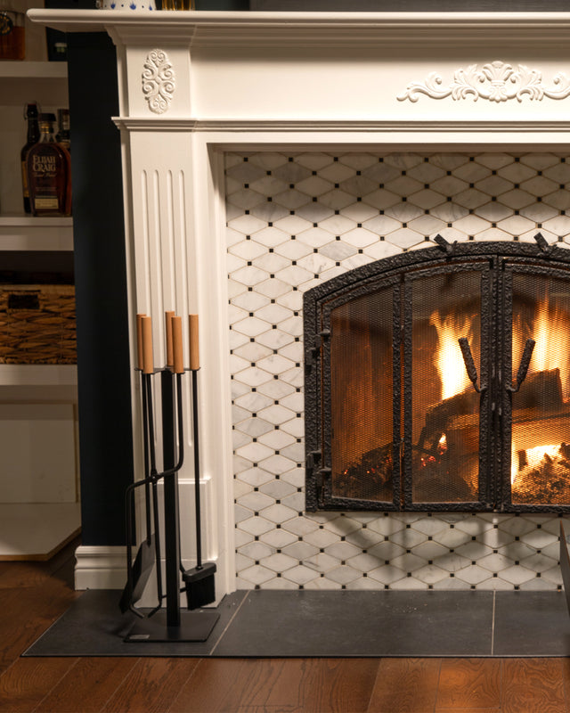 Compact fireplace tool set with wooden handles styled beside a antique fireplace in a warm victorian living room.
