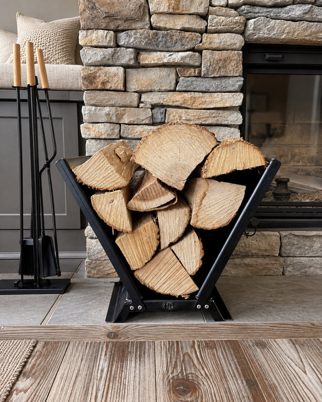 V-shaped steel firewood rack filled with logs beside a stone fireplace and fireplace tools