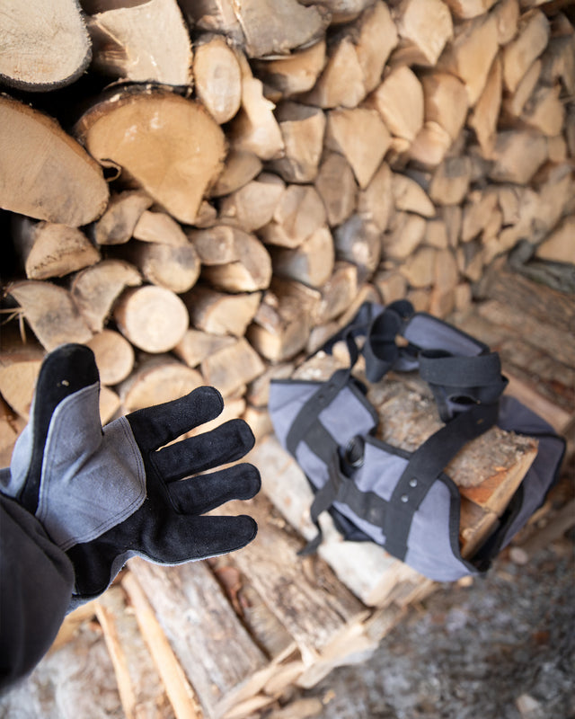 Take-Out Kit with heat-resistant leather gloves and firewood carrier bag beside stacked logs