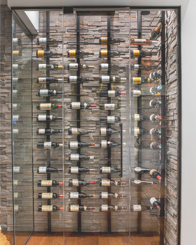 Custom Orford wine columns installed in a luxury glass wine cellar with natural stone wall, handcrafted modular wine storage system made in Québec, Canada.