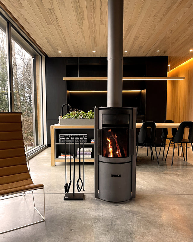 The Rack Co Black Iron fireplace tool set beside a modern fireplace in a Scandinavian-style cabin interior.