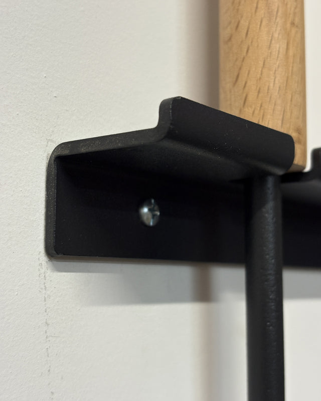 Close-up of the heavy-duty black steel wall bracket used to securely store fireplace tools off the floor.