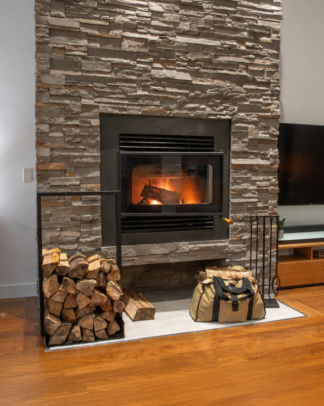 Lumberjack Kit with Nordic firewood rack, fireplace tools and canvas log carrier beside a wood-burning fireplace