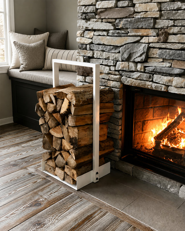 White Nordic firewood rack filled with logs beside a stone fireplace in a modern rustic interior.